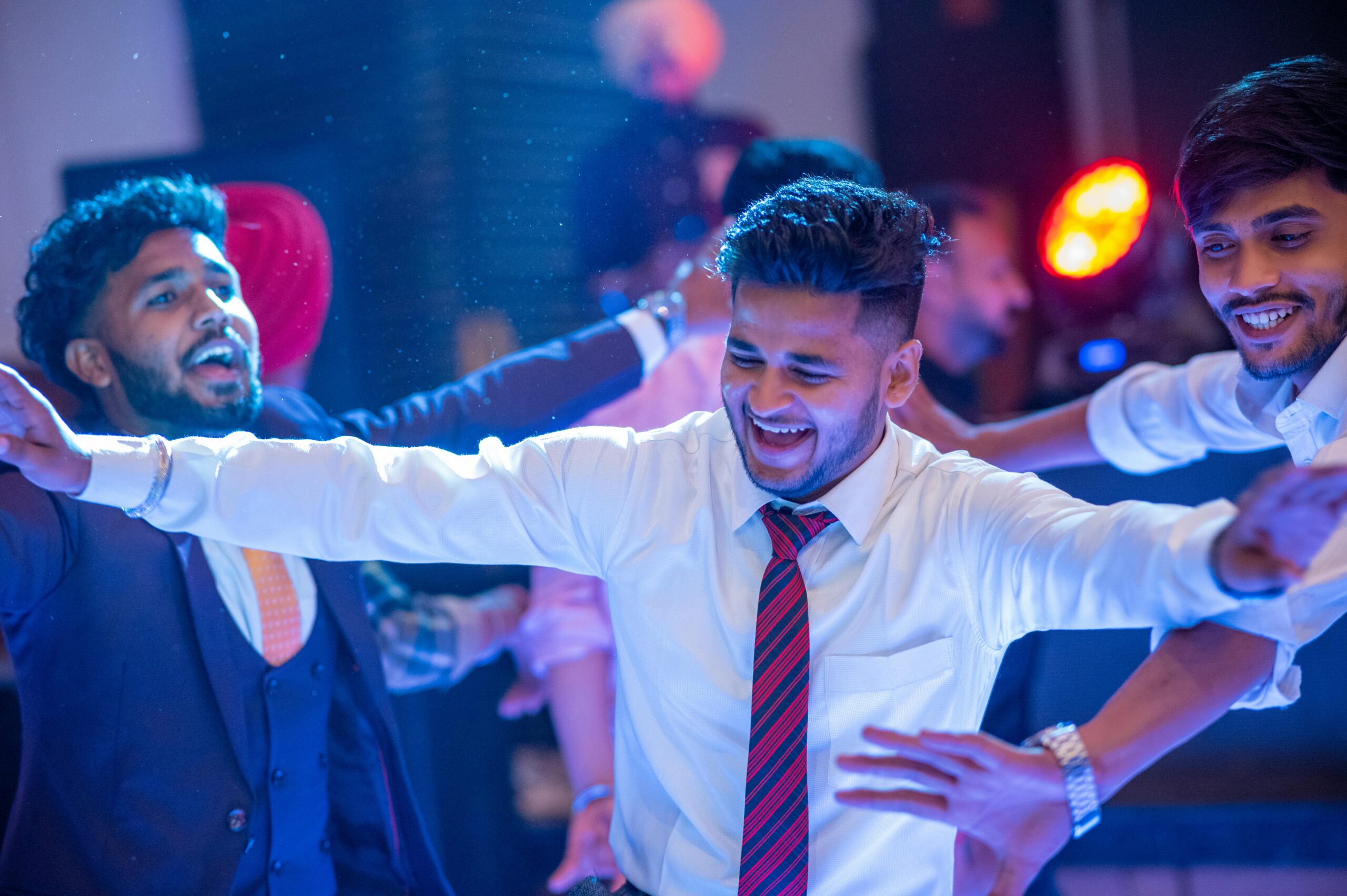 Group of friends enjoying a party with vibrant disco lights, showing joyful expressions.